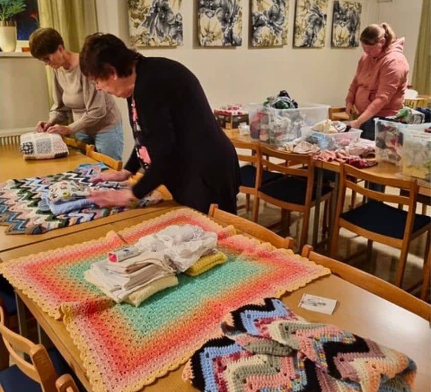 Tre kvinnor som jobbar med textilier.